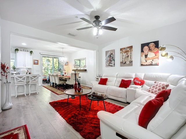 living room with ceiling fan, light wood finished floors, and visible vents