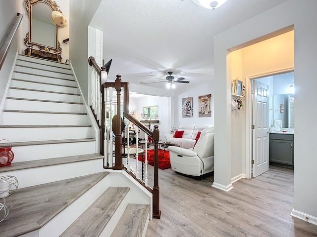 staircase featuring ceiling fan, baseboards, and wood finished floors