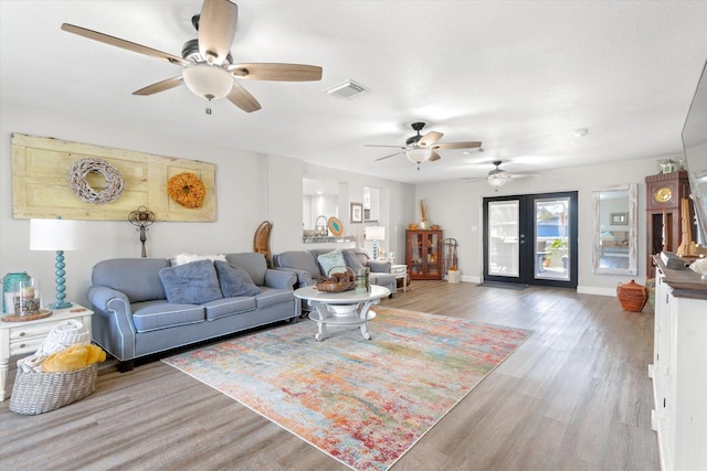 living room with ceiling fan, french doors, and light hardwood / wood-style floors