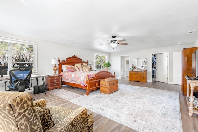 bedroom with ceiling fan, light hardwood / wood-style floors, and a spacious closet