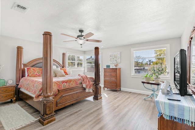 bedroom with multiple windows, ceiling fan, a textured ceiling, and light wood-type flooring