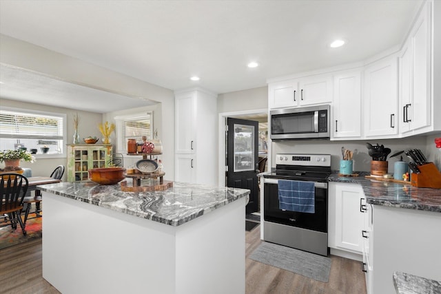 kitchen featuring white cabinetry, stainless steel appliances, and dark stone counters