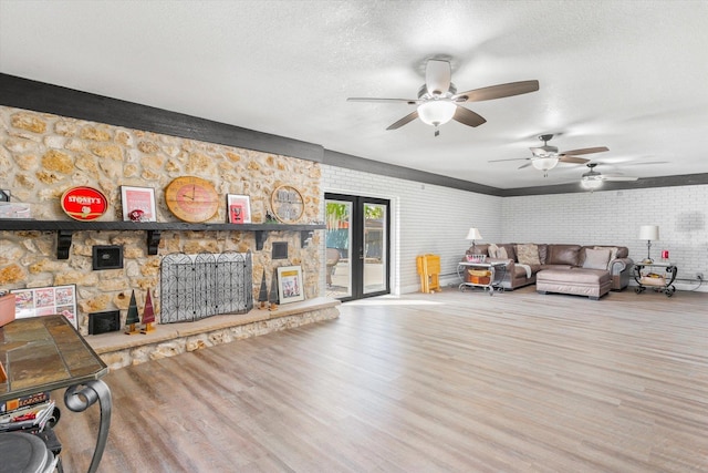 living room with wood-type flooring, a textured ceiling, french doors, and brick wall