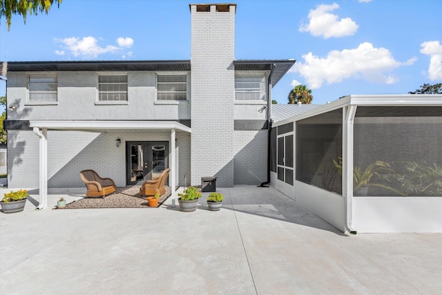 rear view of house featuring a sunroom and a patio