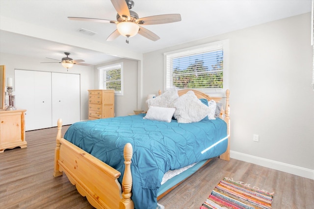 bedroom featuring multiple windows, ceiling fan, a closet, and hardwood / wood-style flooring