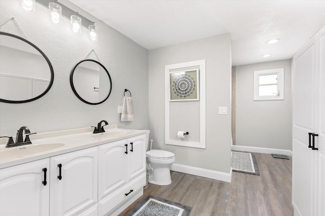 bathroom featuring wood-type flooring, vanity, and toilet