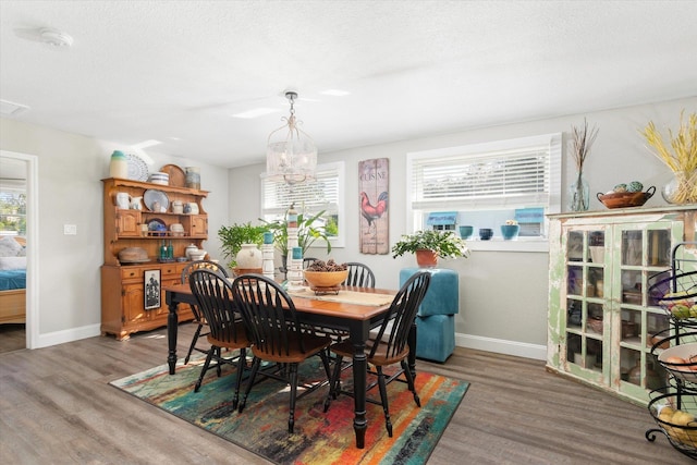 dining area with hardwood / wood-style floors, a textured ceiling, and a notable chandelier