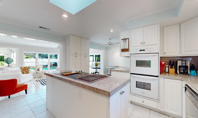 kitchen with white appliances, tasteful backsplash, a center island, light countertops, and white cabinetry