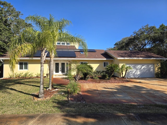 single story home featuring french doors, a front lawn, roof mounted solar panels, and stucco siding