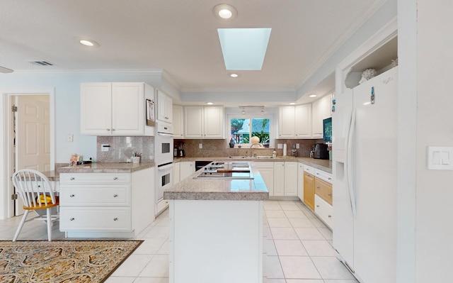 kitchen featuring a skylight, light countertops, visible vents, a sink, and white appliances