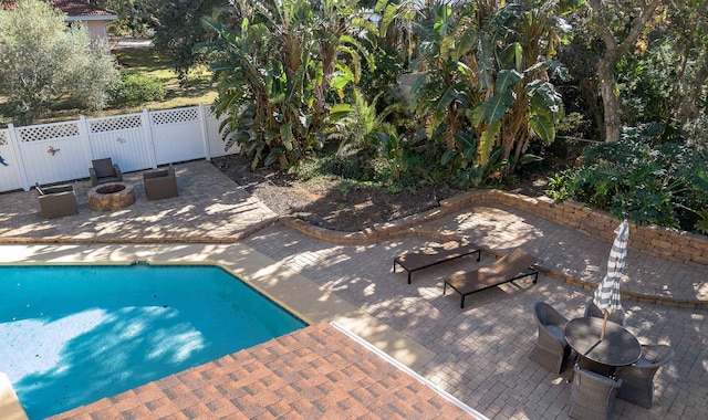 view of swimming pool with a fire pit, fence, a fenced in pool, and a patio