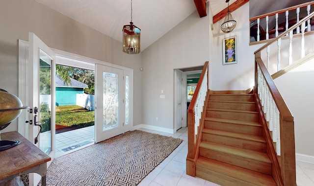 foyer entrance featuring high vaulted ceiling, stairway, a notable chandelier, and tile patterned floors