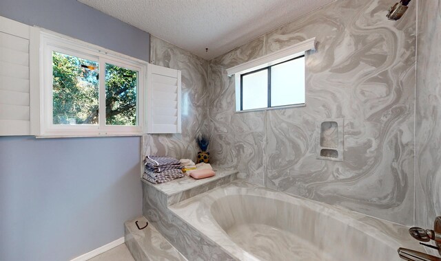 full bathroom featuring a garden tub, baseboards, and a textured ceiling