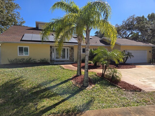 view of front of home featuring solar panels, a garage, a front yard, and french doors