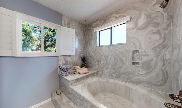 full bathroom featuring a garden tub, a textured ceiling, and baseboards