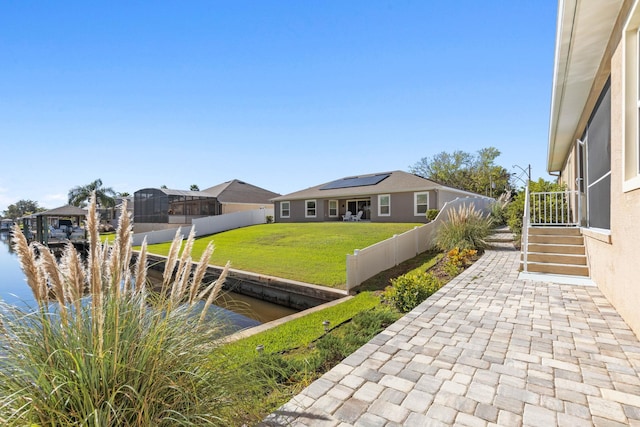 view of yard featuring a dock, a water view, fence, and a patio