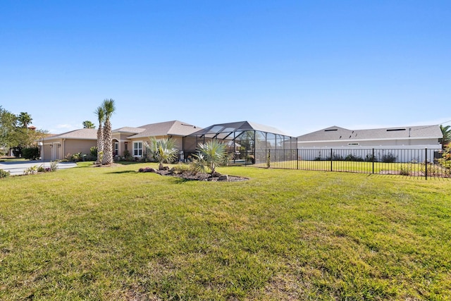 view of yard with a garage, glass enclosure, and fence