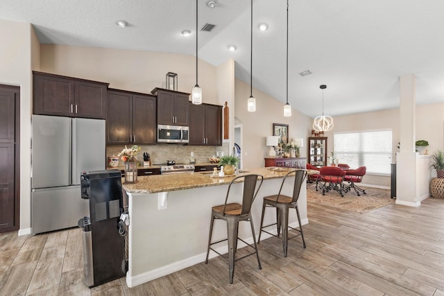 kitchen featuring light wood finished floors, stainless steel appliances, and dark brown cabinets