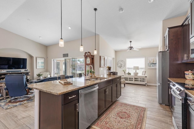 kitchen with appliances with stainless steel finishes, a sink, light wood finished floors, and dark brown cabinetry