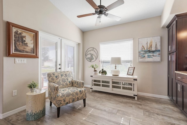 living area with light wood-type flooring, baseboards, a ceiling fan, and lofted ceiling