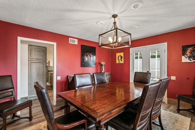 4 Santa Maria Ln, Saint Augustine, FL 32080 - dining space featuring a textured ceiling, a chandelier, light wood-style flooring, french doors, and a textured wall