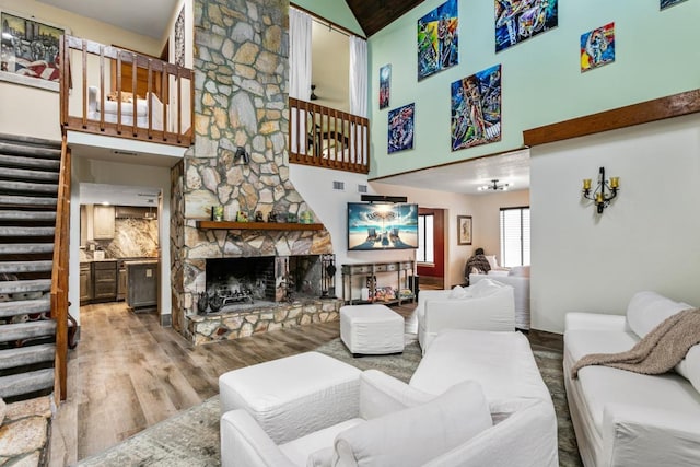 4 Santa Maria Ln, Saint Augustine, FL 32080 - living room featuring stairway, light wood finished floors, a stone fireplace, and high vaulted ceiling