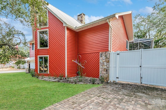4 Santa Maria Ln, Saint Augustine, FL 32080 - view of side of home with a gate, a chimney, stone siding, and metal roof