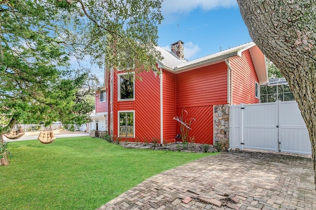 4 Santa Maria Ln, Saint Augustine, FL 32080 - view of home's exterior with metal roof, a gate, a chimney, and stone siding