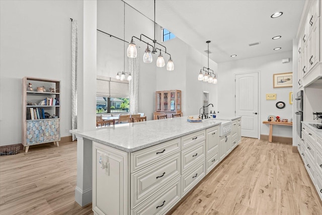 3 Menorca Way, Palm Coast, FL 32137 - kitchen featuring white cabinets, light wood-style floors, a towering ceiling, a chandelier, and recessed lighting
