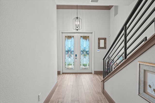 3 Menorca Way, Palm Coast, FL 32137 - entrance foyer featuring a chandelier, stairway, french doors, light wood finished floors, and a textured wall