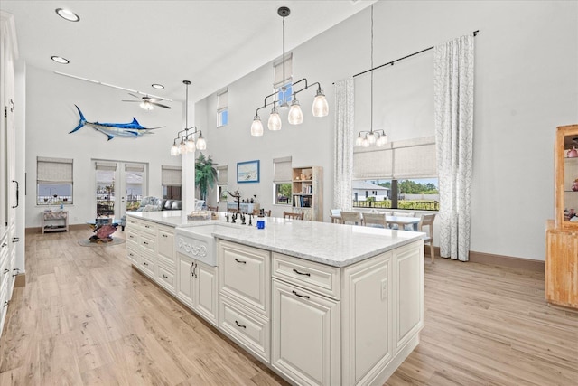 3 Menorca Way, Palm Coast, FL 32137 - kitchen with a high ceiling, a ceiling fan, light wood finished floors, white cabinetry, and light stone countertops