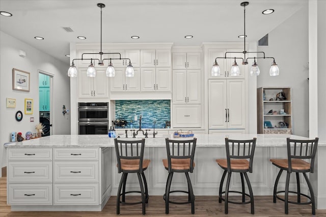 3 Menorca Way, Palm Coast, FL 32137 - kitchen featuring double oven, tasteful backsplash, white cabinetry, light stone countertops, and hanging light fixtures