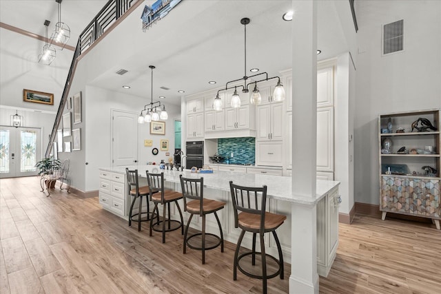 3 Menorca Way, Palm Coast, FL 32137 - kitchen featuring light wood-type flooring, a breakfast bar, light stone counters, white cabinetry, and decorative backsplash