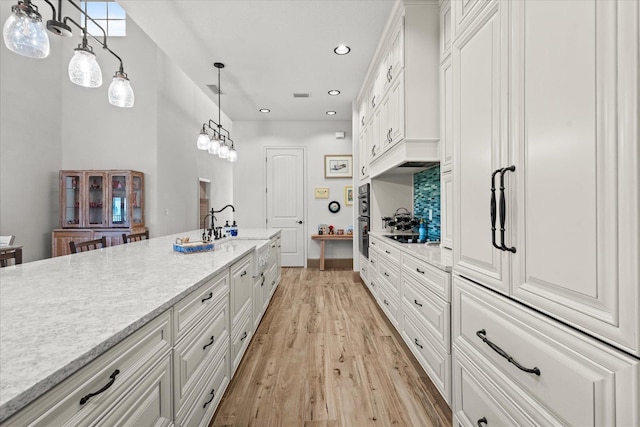 3 Menorca Way, Palm Coast, FL 32137 - kitchen with light wood-style floors, white cabinets, decorative light fixtures, recessed lighting, and light stone countertops