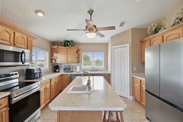 8961 A1A, Saint Augustine, FL 32080 - kitchen featuring stainless steel appliances, an island with sink, light countertops, light tile patterned floors, and a textured ceiling