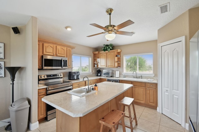 8961 A1A, Saint Augustine, FL 32080 - kitchen featuring appliances with stainless steel finishes, light countertops, a center island with sink, open shelves, and a ceiling fan