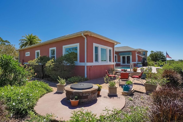 back of house with stucco siding, a patio, fence, and an outdoor fire pit