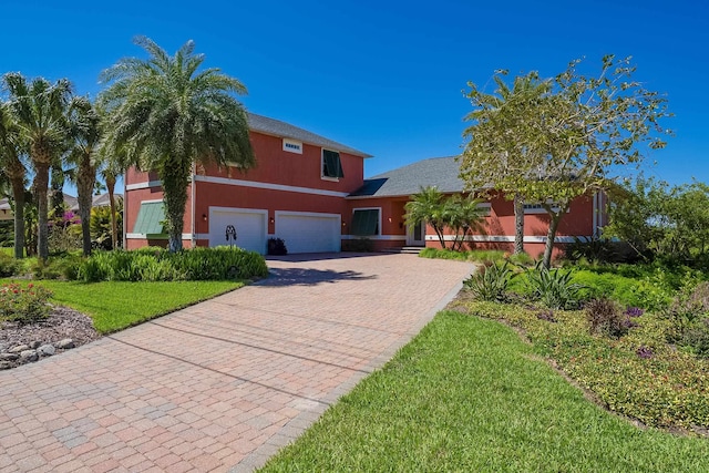 view of front facade with an attached garage, decorative driveway, and a front lawn