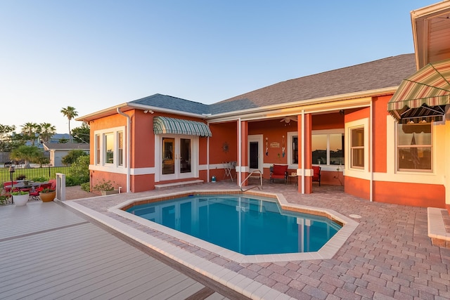 back of property featuring a fenced in pool, a patio, stucco siding, and french doors