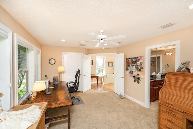 office featuring ceiling fan, light colored carpet, baseboards, and visible vents