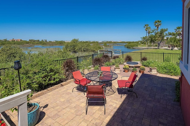 view of patio / terrace with outdoor dining area, a water view, and fence