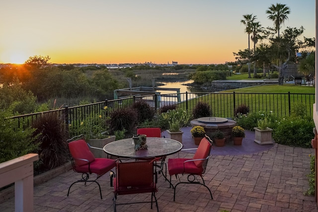 view of patio with fence and a water view
