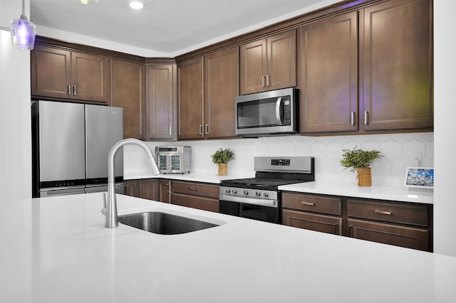 kitchen featuring sink, stainless steel appliances, a textured ceiling, decorative light fixtures, and dark brown cabinets