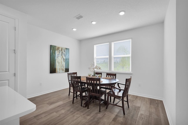 dining room featuring a textured ceiling and dark hardwood / wood-style floors