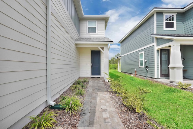 view of exterior entry featuring a lawn