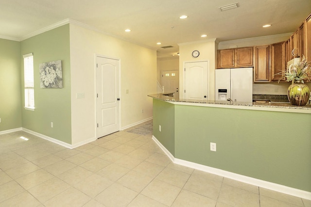 kitchen featuring light stone counters, ornamental molding, light tile patterned floors, and white fridge with ice dispenser