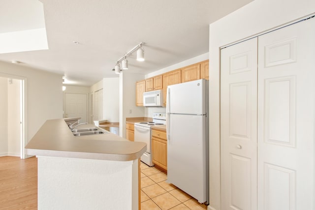 kitchen featuring light brown cabinets, sink, white appliances, and a center island with sink