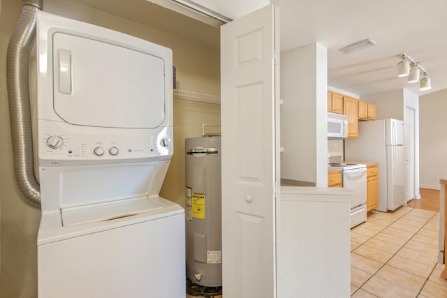 laundry area with stacked washer / drying machine, light tile patterned floors, and water heater