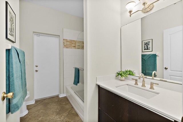 bathroom with a tile shower, tile patterned floors, vanity, and toilet