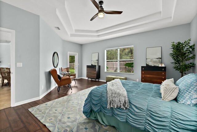 bedroom featuring dark hardwood / wood-style floors, a raised ceiling, and ceiling fan